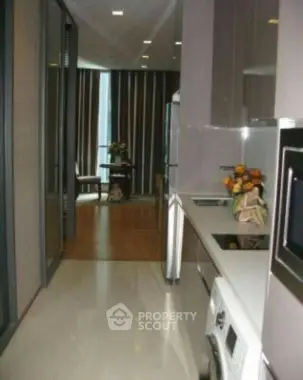 Modern kitchen with sleek appliances and open layout leading to dining area.