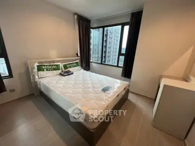 Modern bedroom with large windows and city view, featuring a comfortable bed and sleek design.