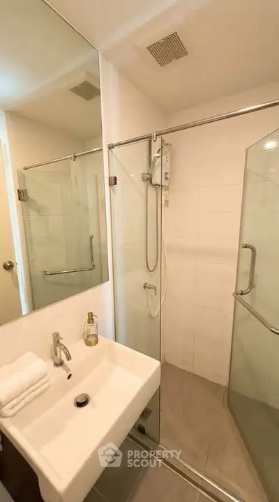 Modern bathroom with glass shower enclosure and sleek fixtures in a contemporary apartment.
