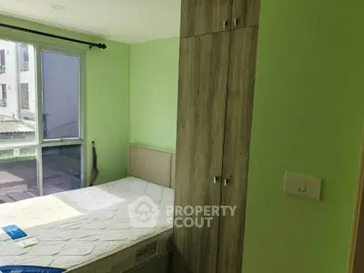 Cozy bedroom with large window and built-in wardrobe in modern apartment.