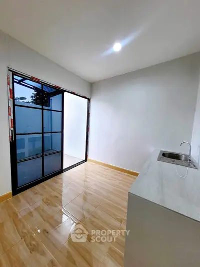 Modern minimalist kitchen with sleek design and sliding glass doors to balcony.