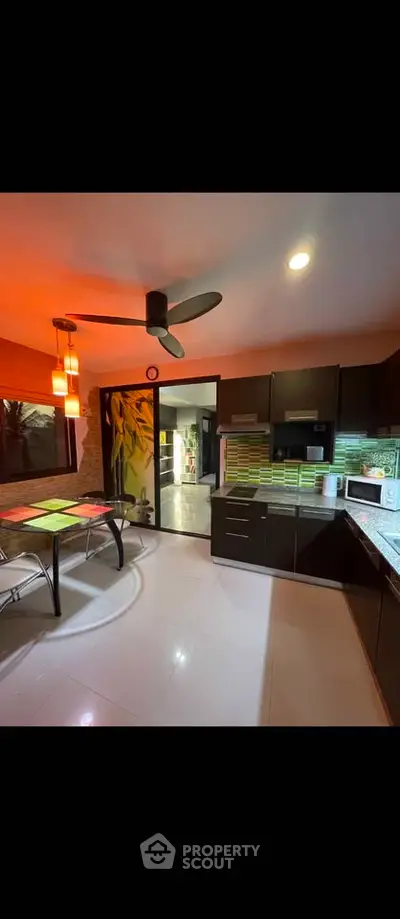 Modern kitchen with sleek cabinetry, ceiling fan, and dining area in a stylish home.