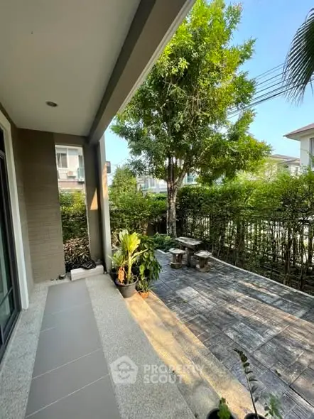 Charming garden view from a modern patio with lush greenery and outdoor seating area.