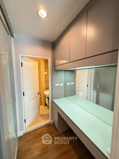 Modern bathroom with sleek cabinetry and glass countertop in stylish apartment.