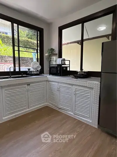 Charming kitchen with modern appliances and ample natural light, featuring sleek cabinetry and a cozy atmosphere.