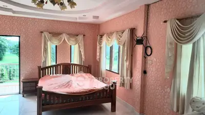 Charming bedroom with elegant drapes and wooden bed, offering serene views through large windows.