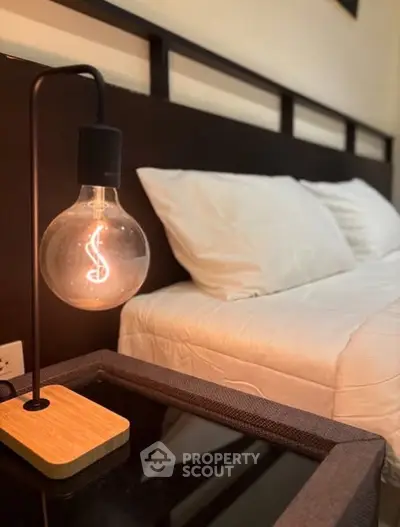 Cozy bedroom with modern lamp and plush bedding, perfect for relaxation.