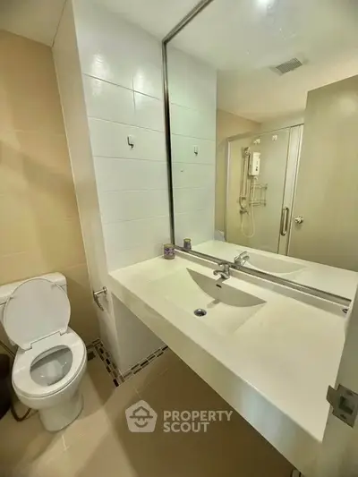 Modern bathroom with sleek design, featuring a large mirror and spacious shower area.