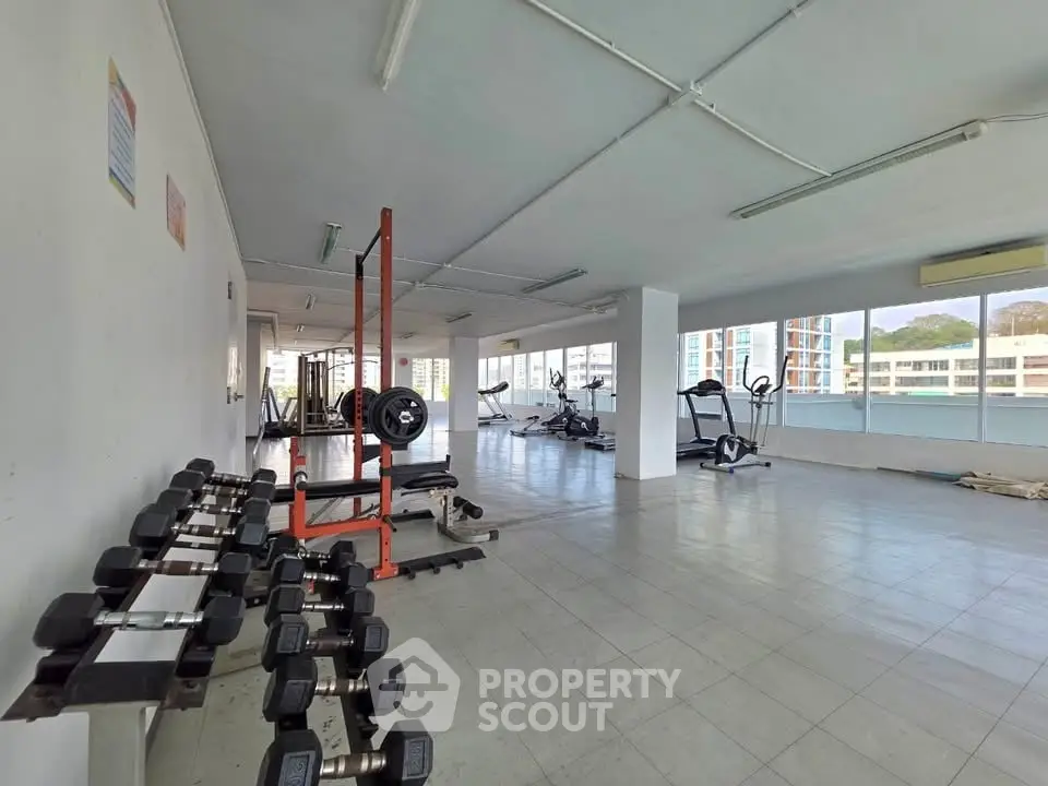 Spacious gym with modern equipment and large windows offering city views