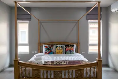 Spacious bedroom with elegant wooden four-poster bed and colorful pillows, perfect for relaxation.