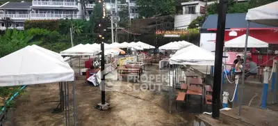 Outdoor dining area with white tents and picnic tables in a scenic setting.