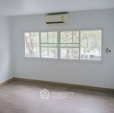 Spacious empty room with large window and air conditioning, perfect for customization.