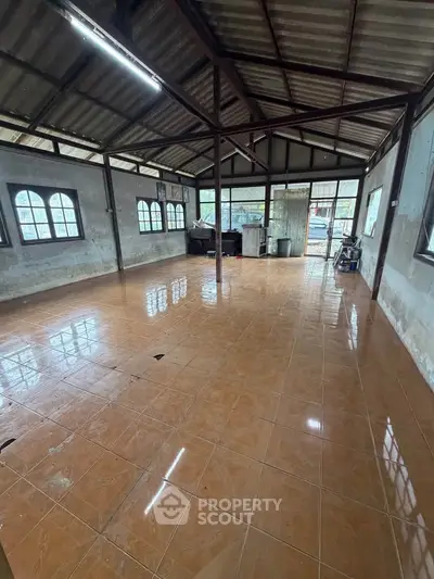 Spacious industrial-style room with tiled flooring and large windows, perfect for creative workspace or studio.