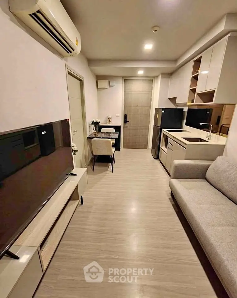 Modern living room with sleek furniture and integrated kitchen appliances in a cozy apartment.