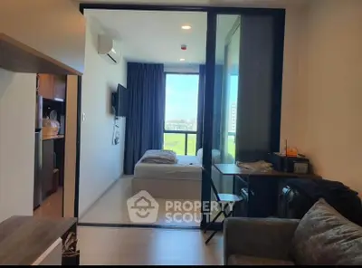 Modern studio apartment with sleek furniture and a large window offering an abundance of natural light and a serene view, perfect for urban living.