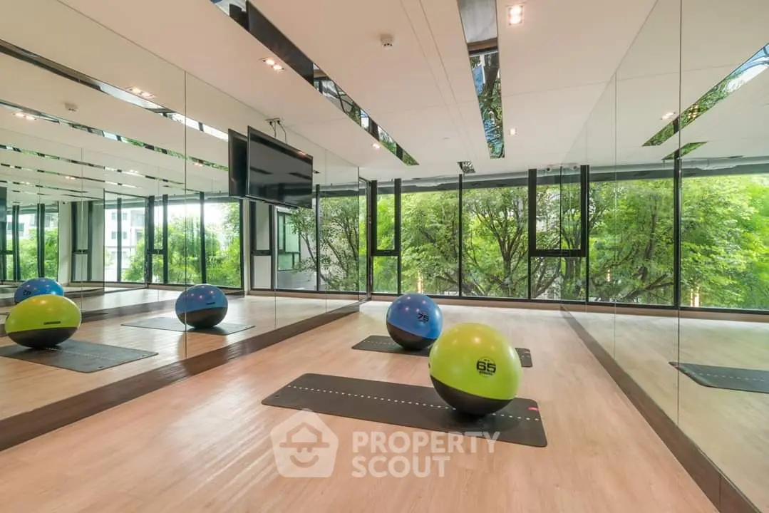 Modern gym with mirrored walls and exercise balls in luxury apartment complex.
