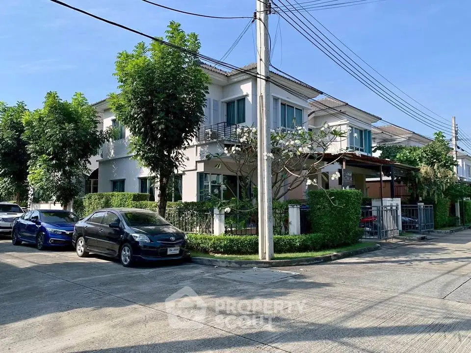 Charming corner unit house with lush greenery and ample parking in a serene neighborhood.