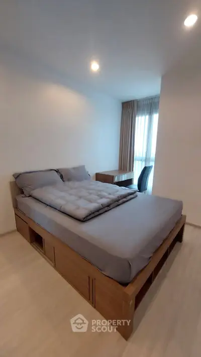 Modern bedroom with sleek design and natural light, featuring a cozy bed and stylish desk area.