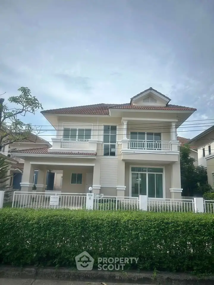 Elegant two-story house with a modern design, featuring a spacious balcony and lush greenery in a serene neighborhood.