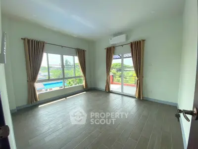 Spacious bedroom with large windows and balcony access, offering natural light and scenic views.