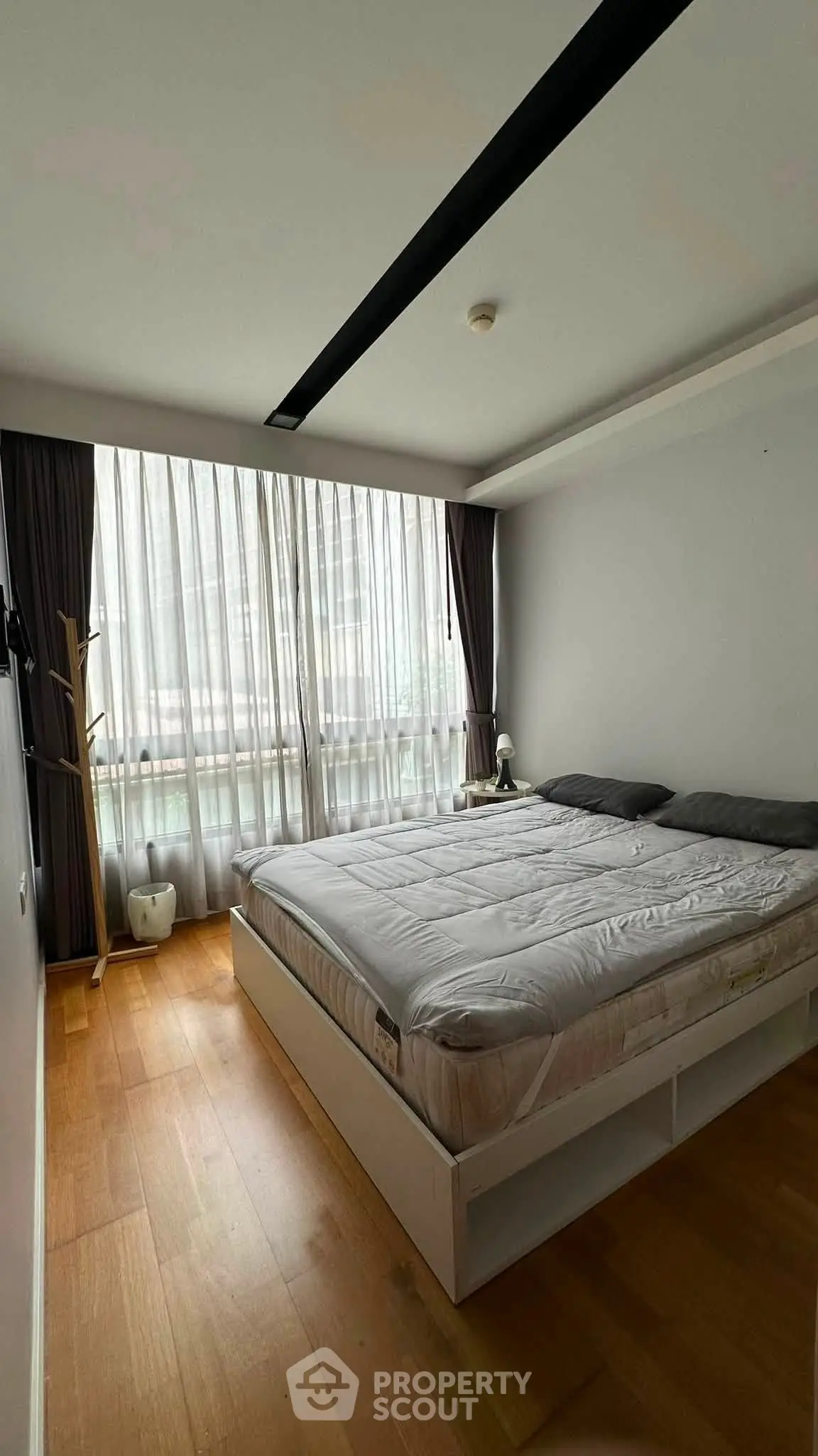 Spacious bedroom with large window and modern decor in a stylish apartment.