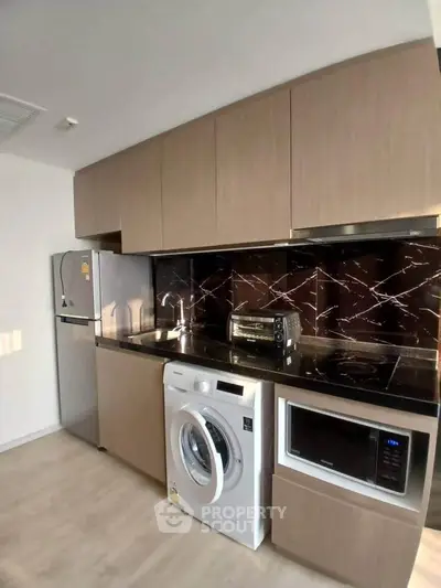 Modern kitchen with sleek cabinets, washing machine, and appliances in a stylish apartment.