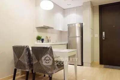 Modern kitchen with sleek design, featuring stainless steel fridge and elegant dining area.
