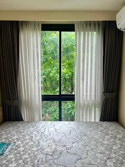 Cozy bedroom with large window and lush green view, perfect for relaxation and natural light.