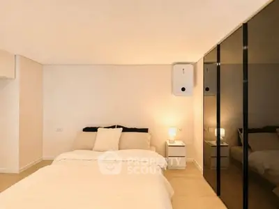Modern bedroom with sleek mirrored wardrobe and cozy lighting, perfect for relaxation and comfort.