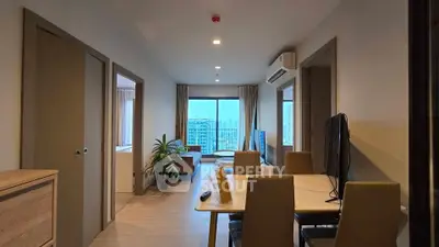 Modern apartment interior with open living and dining area, featuring large windows and city view.