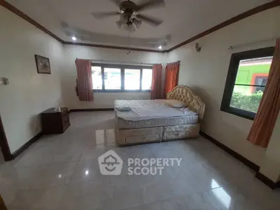 Spacious bedroom with large windows and elegant bed in a bright, airy setting.