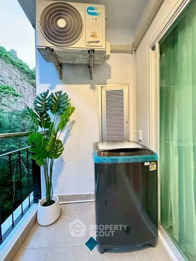 Charming balcony with washing machine and lush greenery view, perfect for urban living convenience.