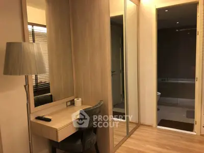 Modern bedroom with elegant vanity and mirrored closet doors, featuring warm lighting and stylish decor.