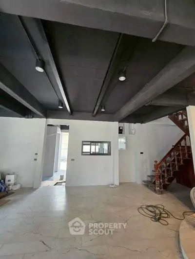 Spacious industrial-style interior with high ceilings and modern staircase, perfect for creative living.