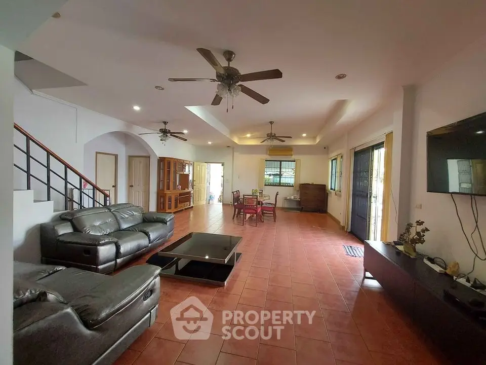 Spacious living room with terracotta tiled flooring, leather couches, and ample natural light, leading to an inviting dining area.
