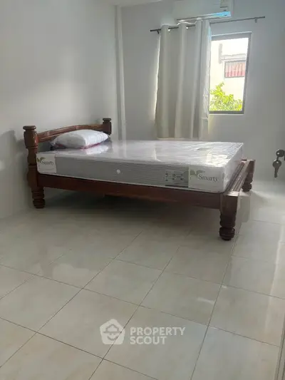 Spacious bedroom with natural light and elegant wooden bed frame, perfect for relaxation.