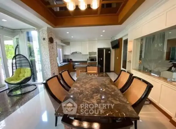 Luxurious dining area with marble table and modern kitchen in open layout design.