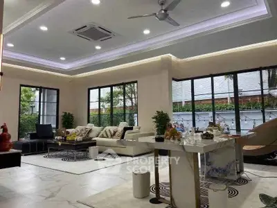 Luxurious modern living room with elegant decor and large windows offering garden views.
