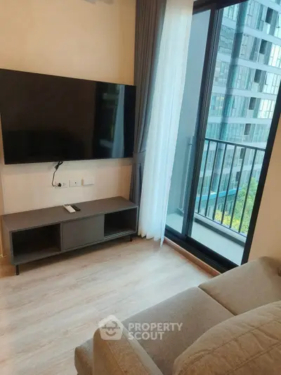 Modern living room with sleek TV setup and balcony view in urban apartment.