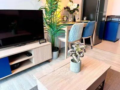 Modern living room with stylish decor, flat-screen TV, and dining area in a cozy apartment.