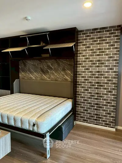 Modern bedroom with stylish brick accent wall and sleek wooden flooring.