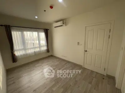 Spacious empty room with wooden flooring and air conditioning, perfect for customization.