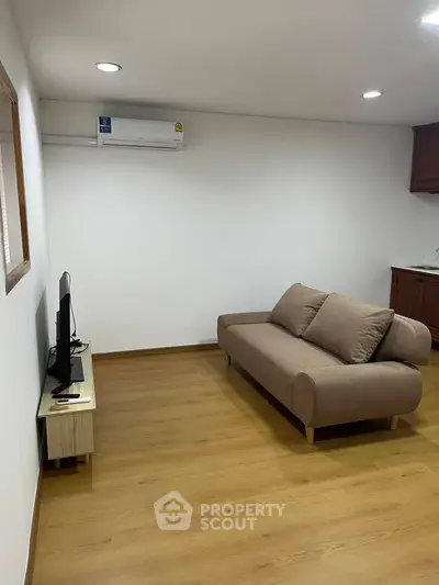 Modern living room with sleek sofa and wall-mounted TV, featuring minimalist design and wooden flooring.