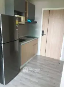 Modern kitchen with sleek appliances and wooden cabinetry in a compact apartment.