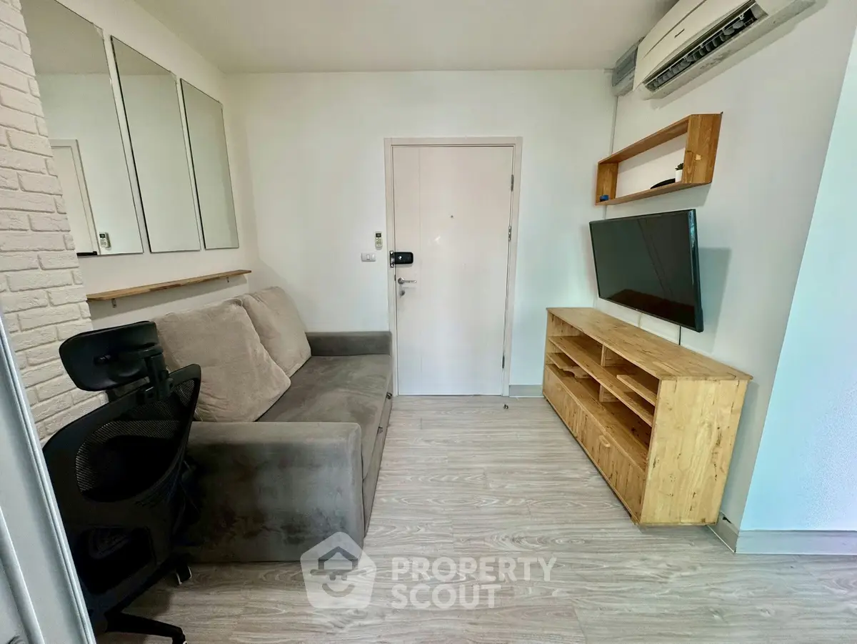 Cozy living room with modern decor, featuring a plush sofa, wall-mounted TV, and stylish shelving.