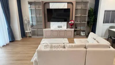 Elegant living room with modern decor, large TV, and stylish shelving, perfect for relaxation and entertainment.