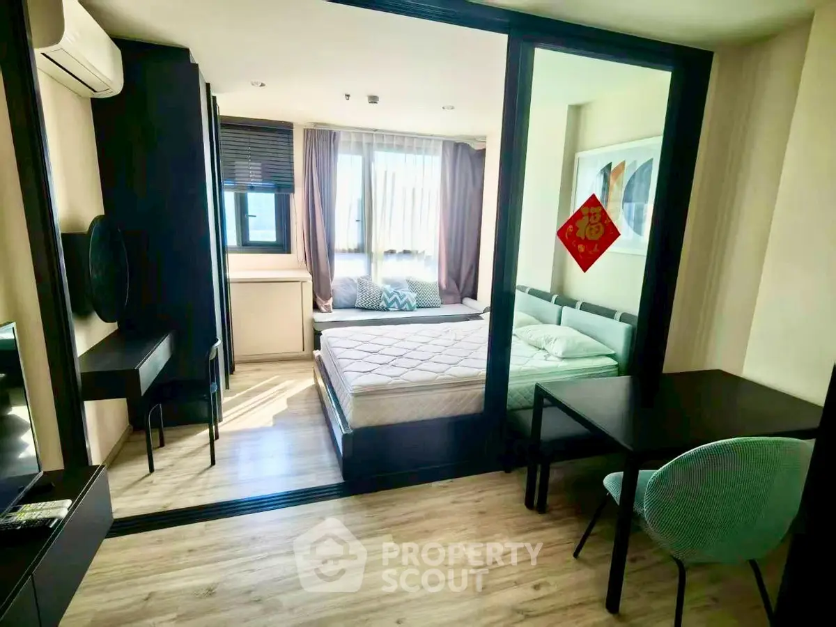 Modern bedroom with large window and stylish decor in a cozy apartment.
