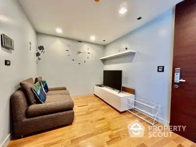 Modern living room with stylish decor and wall-mounted TV, featuring cozy seating and wooden flooring.