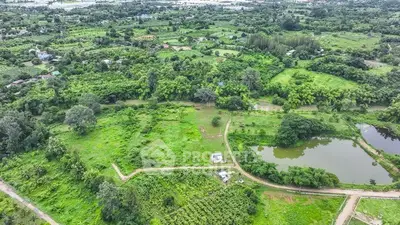Expansive aerial view of lush green land with ponds, ideal for development opportunities.