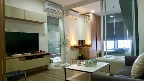 Modern living room with stylish decor and open view into bedroom, featuring sleek furniture and ambient lighting.